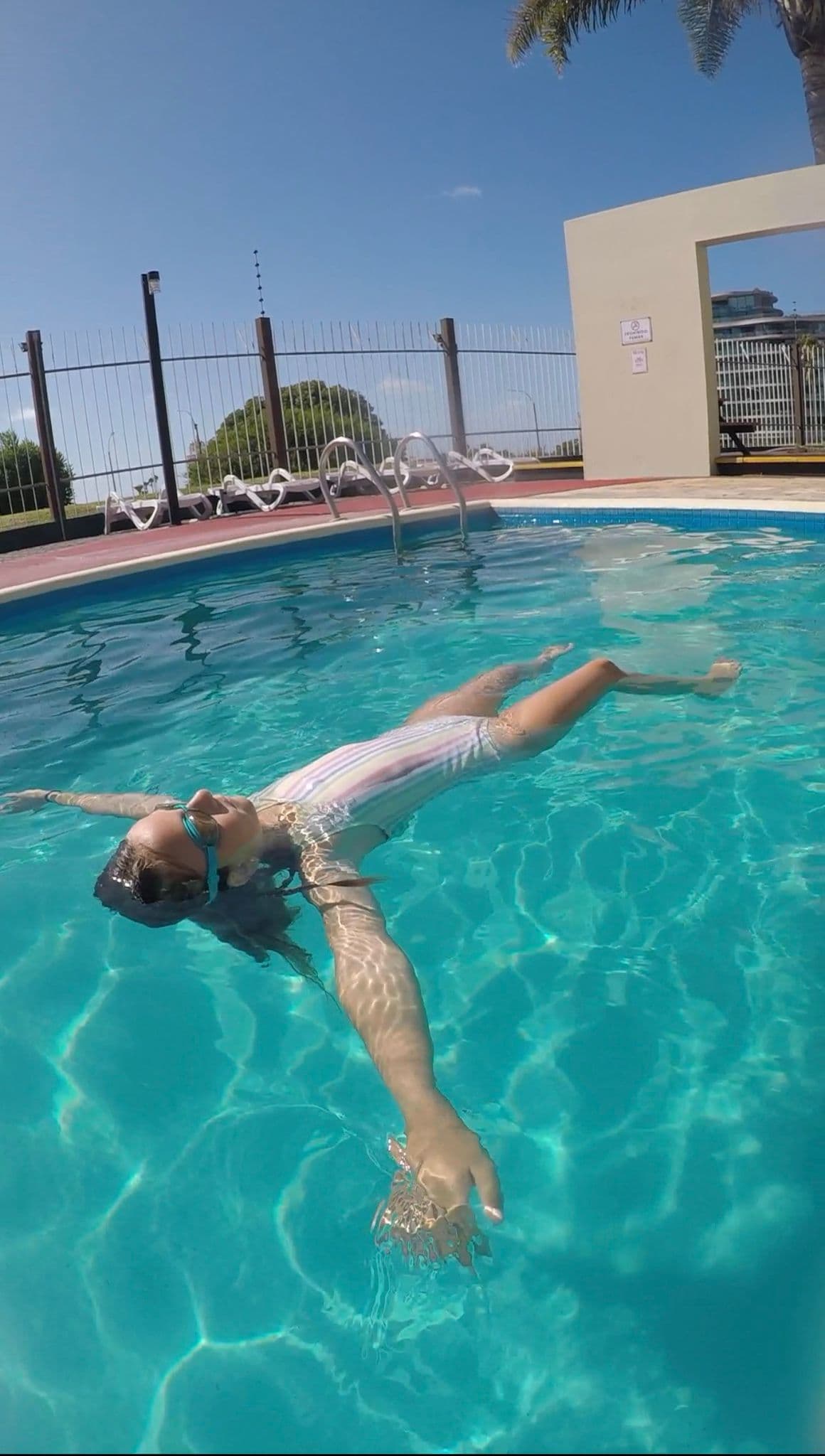 Nena flotando de espaldas en una pileta al aire libre
